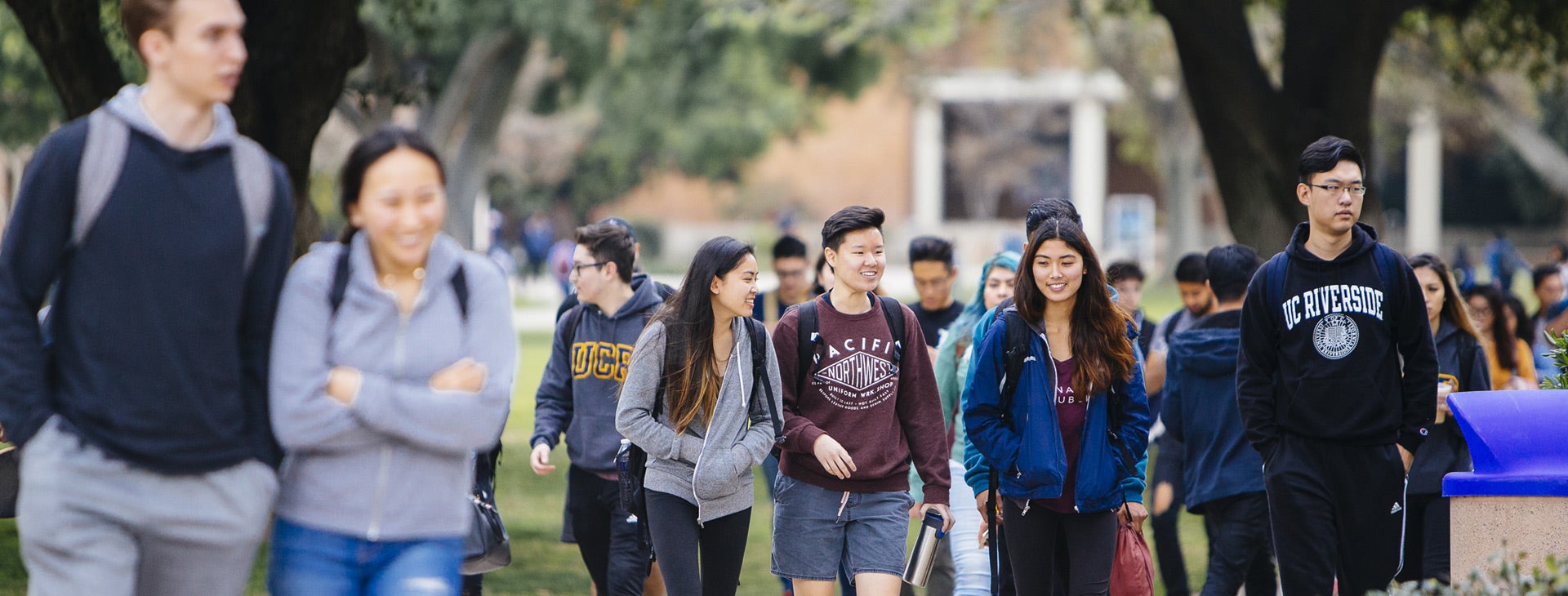 A large group of students walk across the UCR campus.